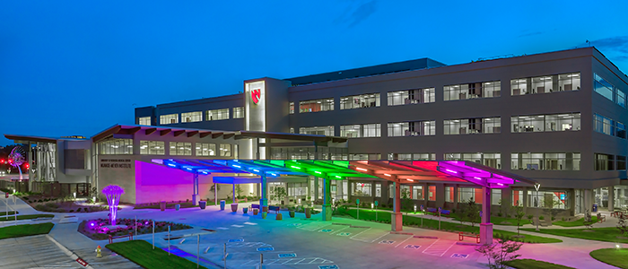 Munroe-Meyer Institute building at night with rainbow pride LED canopy lighting