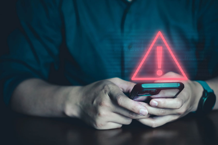 Person holding cell phone with hazard symbol above it