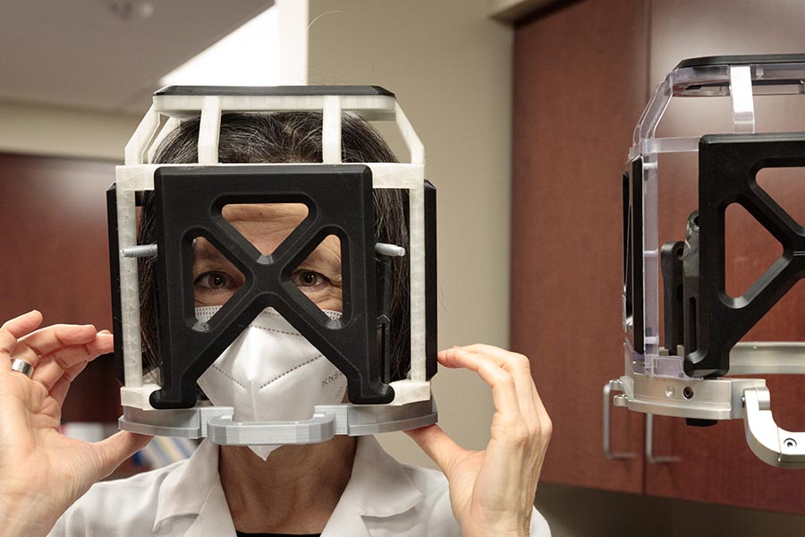 Aviva Abosch, MD, PhD, chair of the UNMC Department of Neurosurgery, dons the head frame and box models.