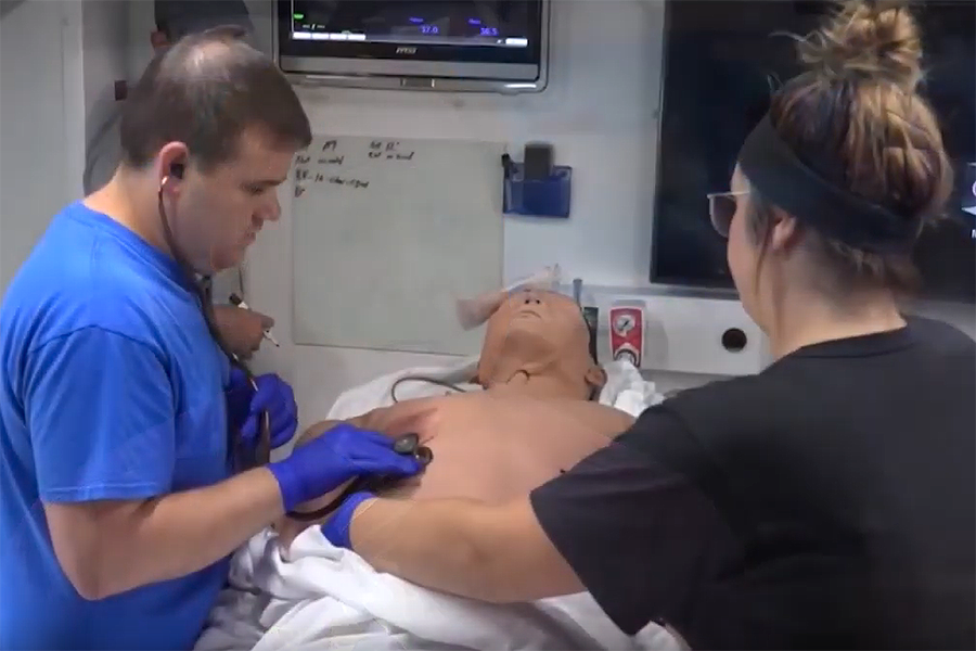 First responders practice giving CPR to a manikin in a simulated emergency room in a SIM-NE truck.