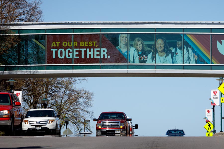A banner in a pedestrian overpass at UNMC reads "At Our Best Together"