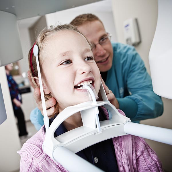 Dentist taking dental x-ray of young girl