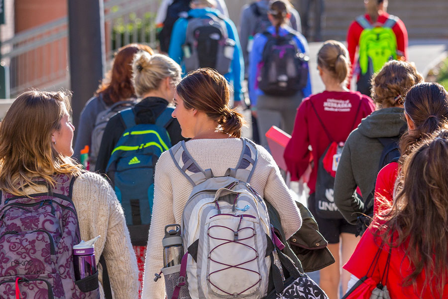 Students wearing backpacks walking across the street