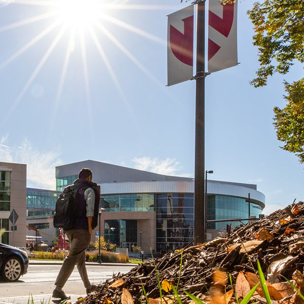 Student walking on sidewalk in sunshine