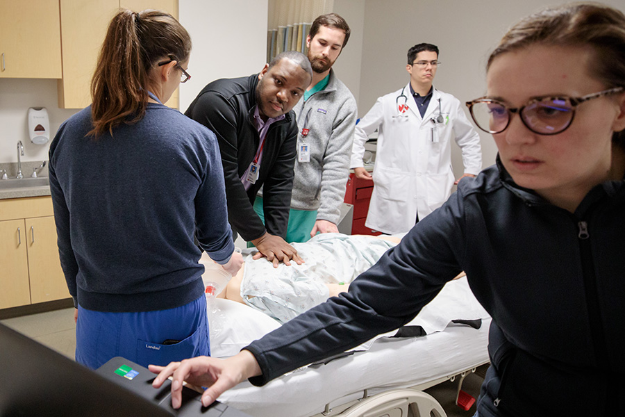 Interprofessional group of students practice in a patient room