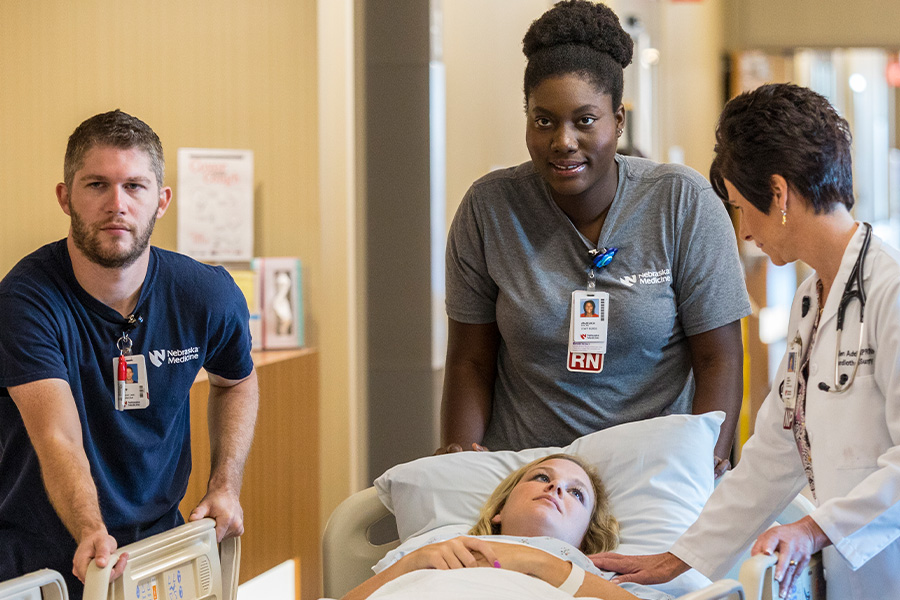 Two nursing students stand at the bedside of a patient