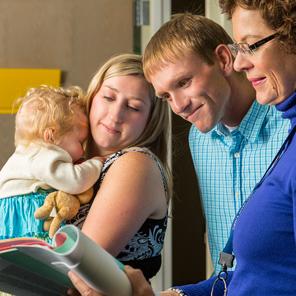 Mother and father hold child while doctor explains test results