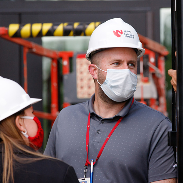 Man and woman stand in construction site wearing hard hats