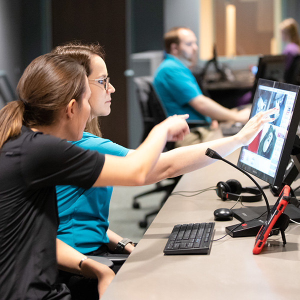 Two students look at images and data on a computer screen