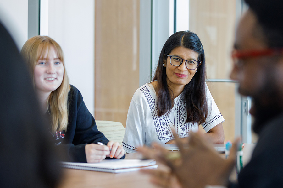 Public health professional sits at a table talking to colleagues