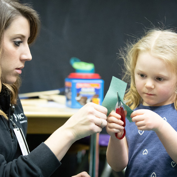 Woman holding piece of paper while child cuts it in half