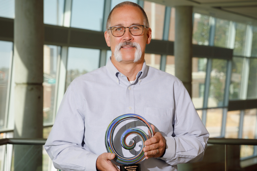 Jesse Boyd poses in atrium holding the catalyst award.