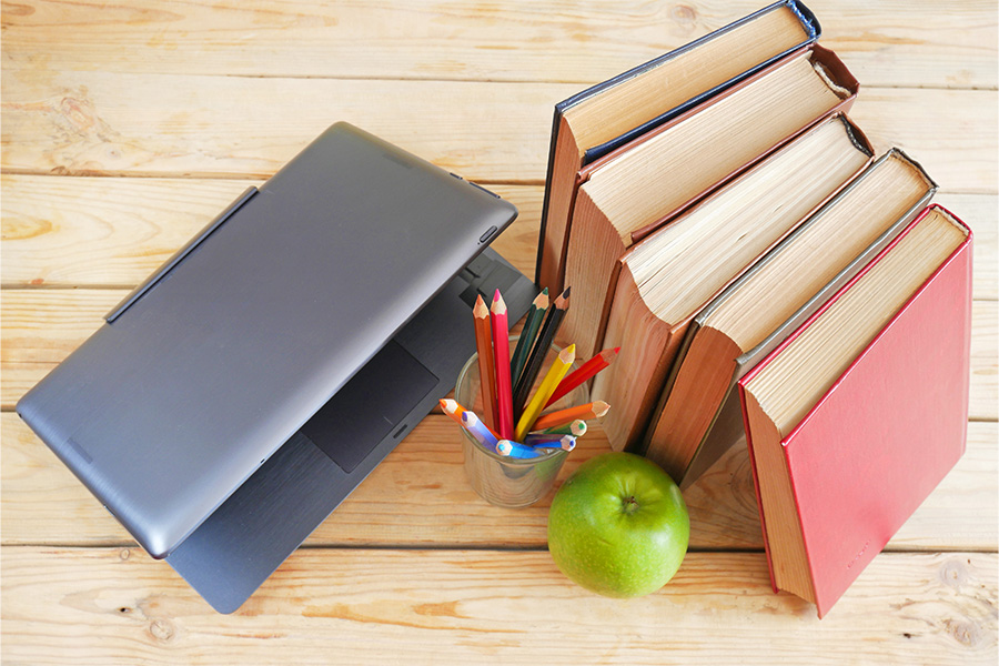 Books and laptop on desk to signify curriculum
