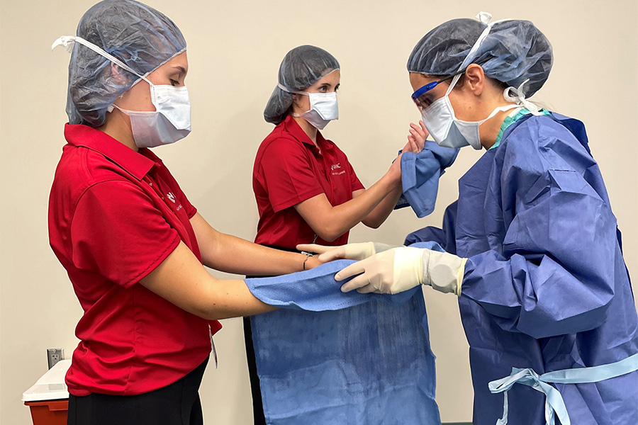 Students learn the importance of drying their hands before donning personal protective equipment for surgeryues to students