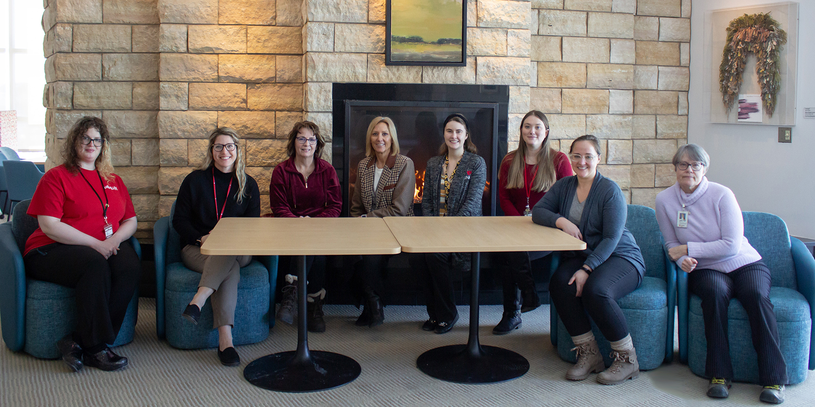 Group of women after a Potluck sitting at a table in front of a fireplace