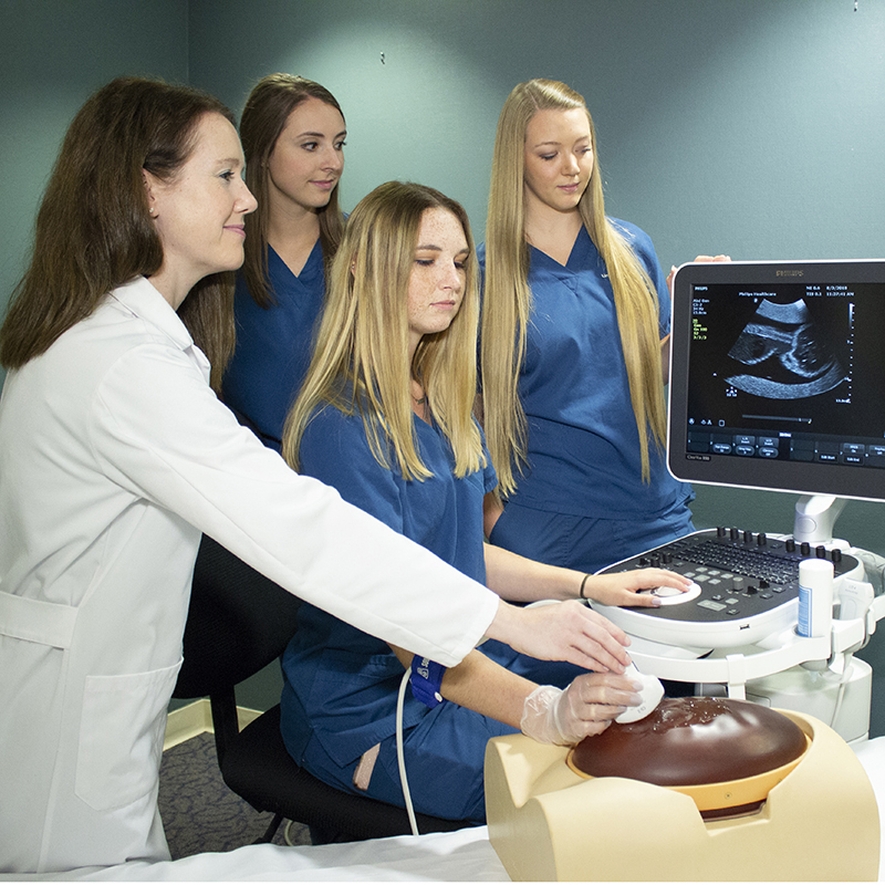 Sonography instructor with students and phantom