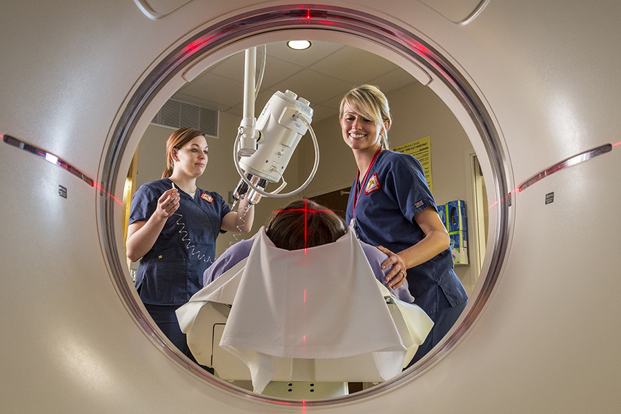 Techs move a patient into the CT scanner