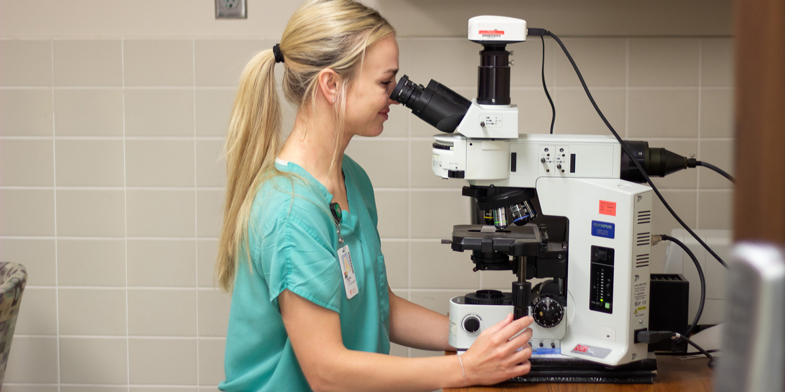 Diagnostic Cytologist at a microscope in a lab