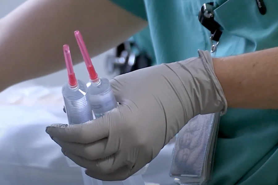 Latex gloved hands holding syringes.