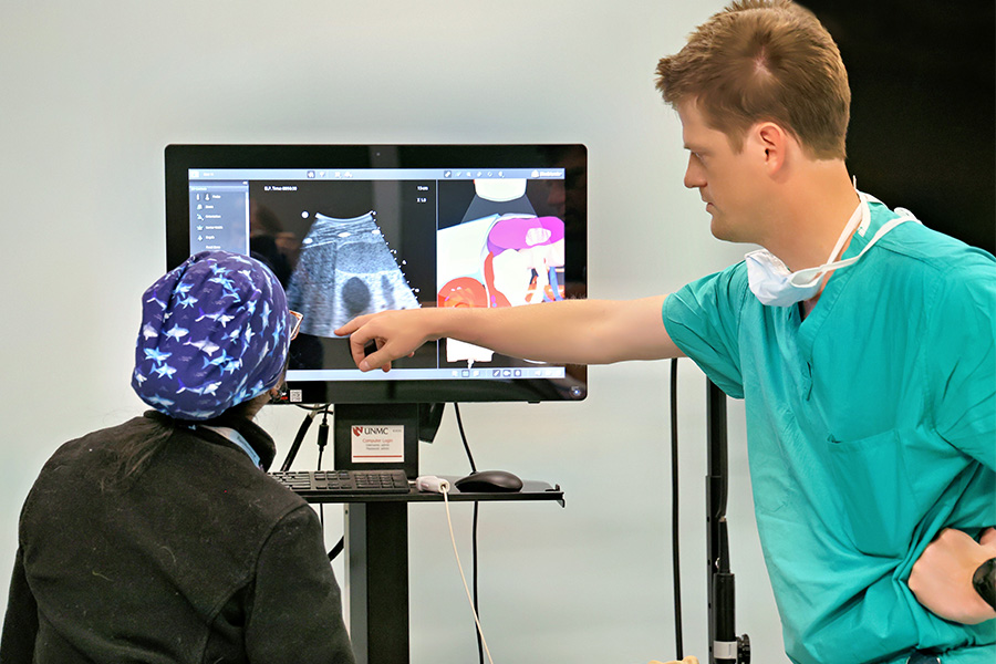 Residents perform ECHO simulation, one is pointing to an image on a screen.