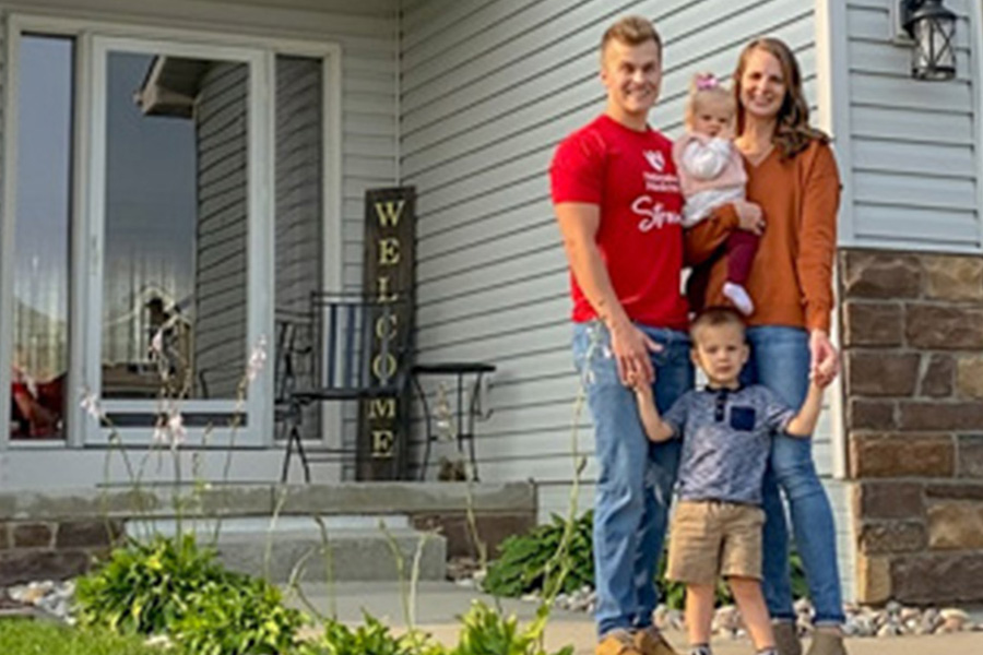 Photo of resident posing with wife and baby in front of home