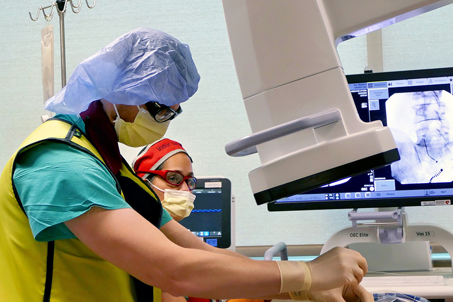 Peter Pellegrino, MD, PhD, and pain medicine division chief, Madhuri Are, MD, perform a procedure in the pain clinic.