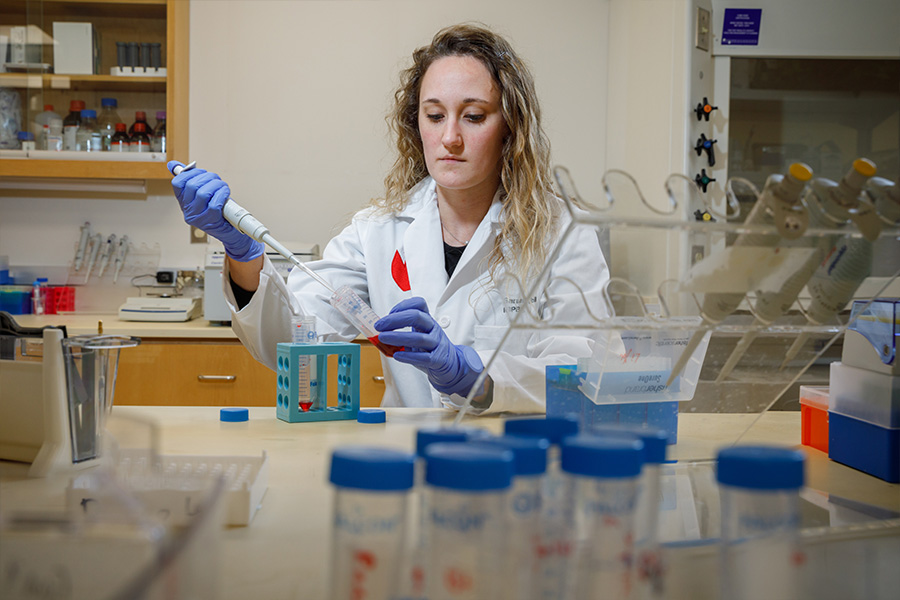 Sarah Pribil in white lab coat working in lab