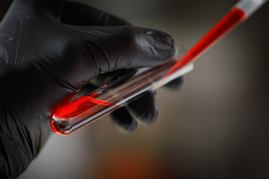 Photo of a latex glove covered hand holding a test tube