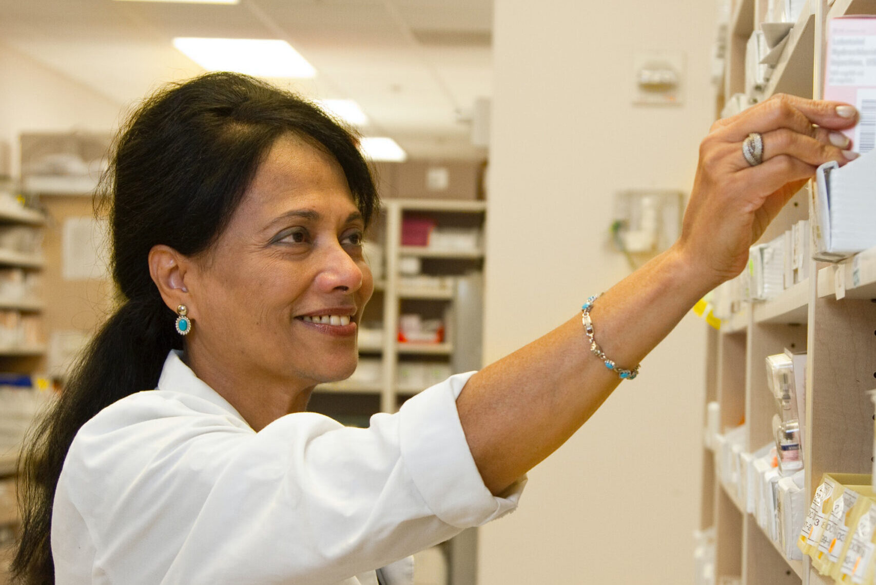 Doctor grabbing a medication from a shelf