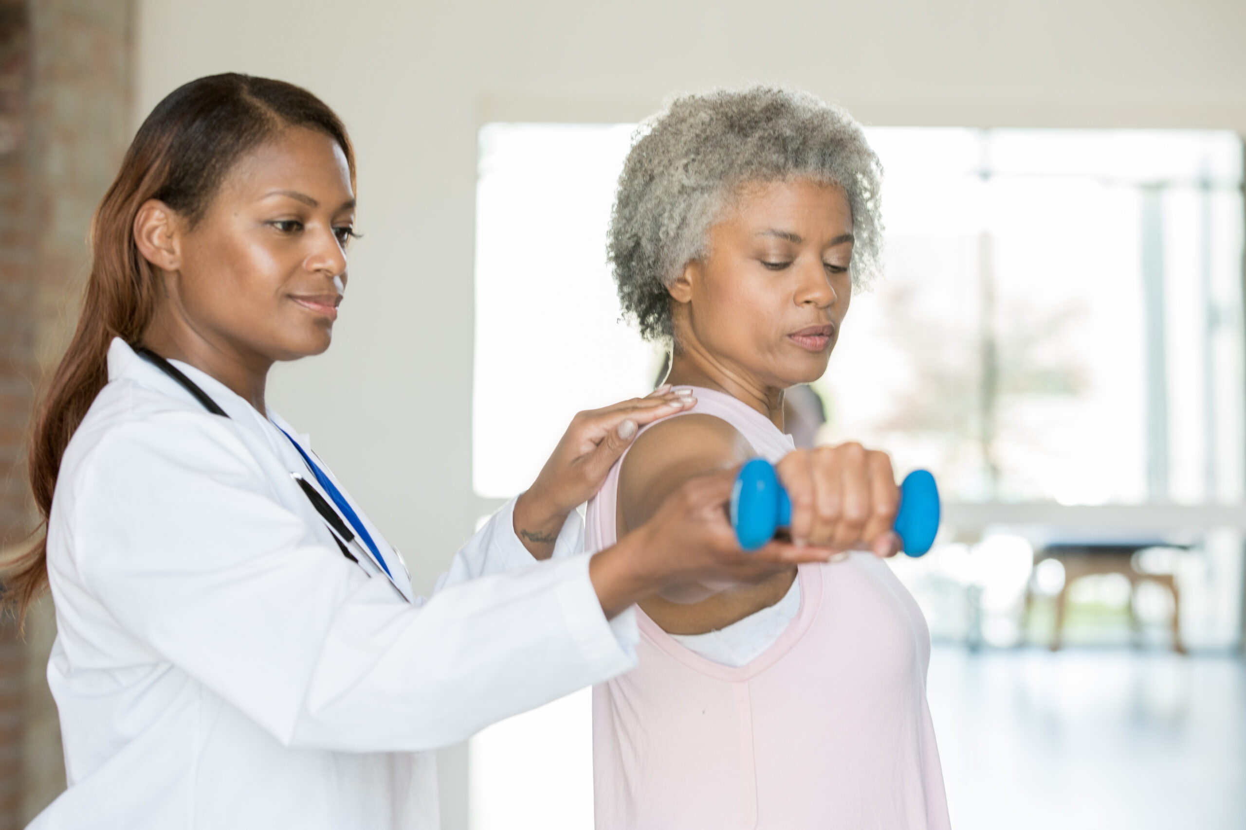 Physical therapist helping senior woman with wrist strengthening