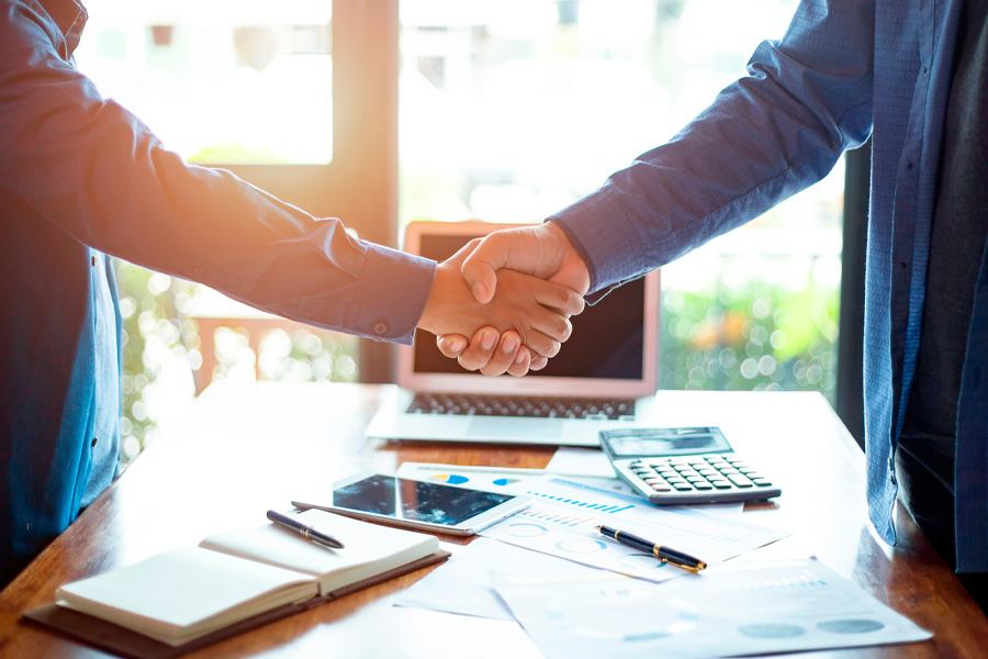 Two people shake hands over a table