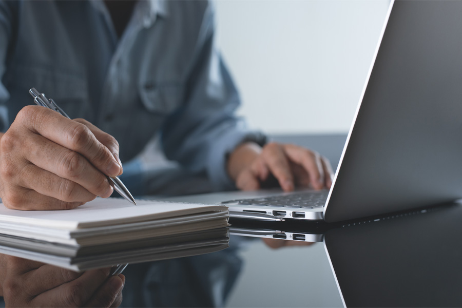 A person, seen from the neck down, works at a laptop