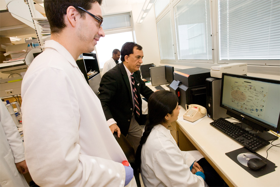 Two students review lab results with Dr. surinder Batra