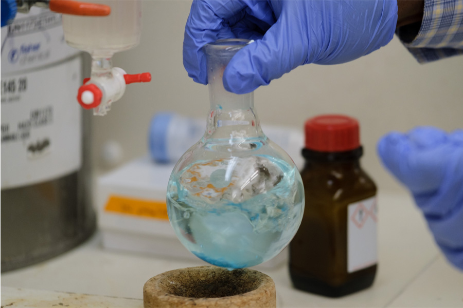 A researcher wearing gloves uses lab equipment