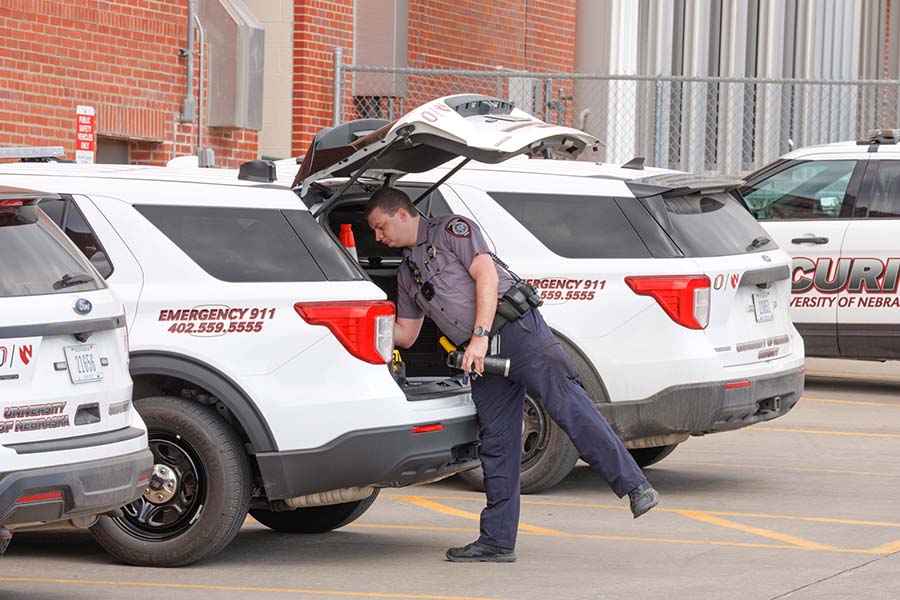 UNMC security officer retrieves equipment from the back of his white security cruiser.