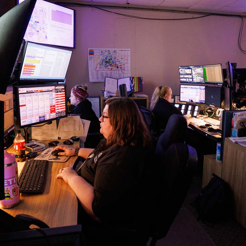 Three dispatchers work at computers in the UNMC Police Dispatch Center.