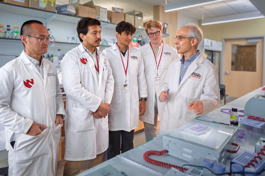A research faculty member speaking with students in his laboratory