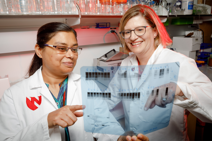 Two researchers in white lab coats look at a sheet of results