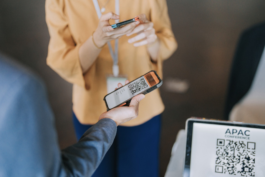 Two people using mobile phones to register through QR codes