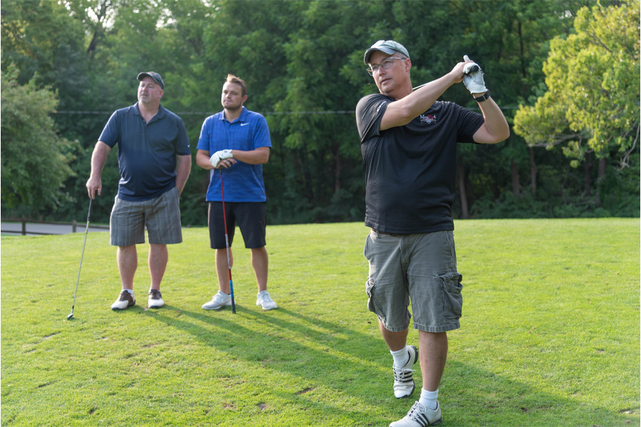 Three people play golf outdoors