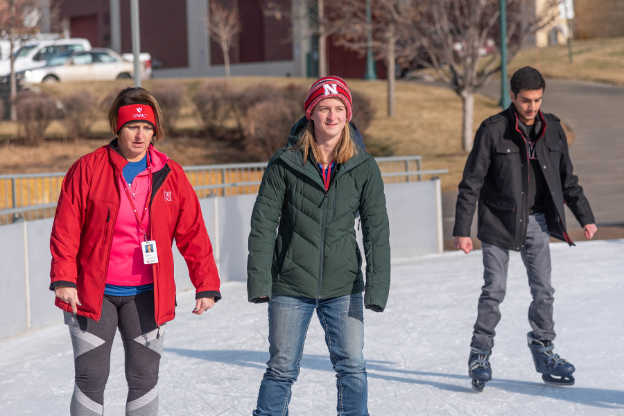 Three students skate on the ice rink