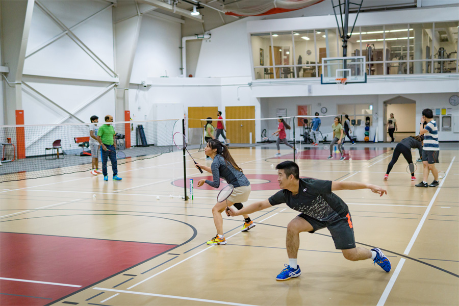 Students play badminton in a gymnasium