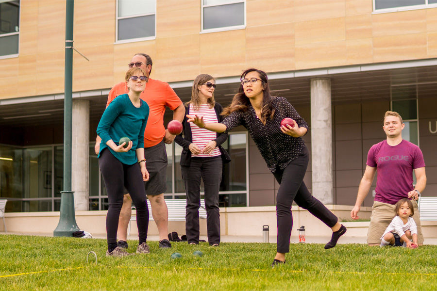 A group of people play bocce ball in the Ruth and Bill Scott Student Plaza