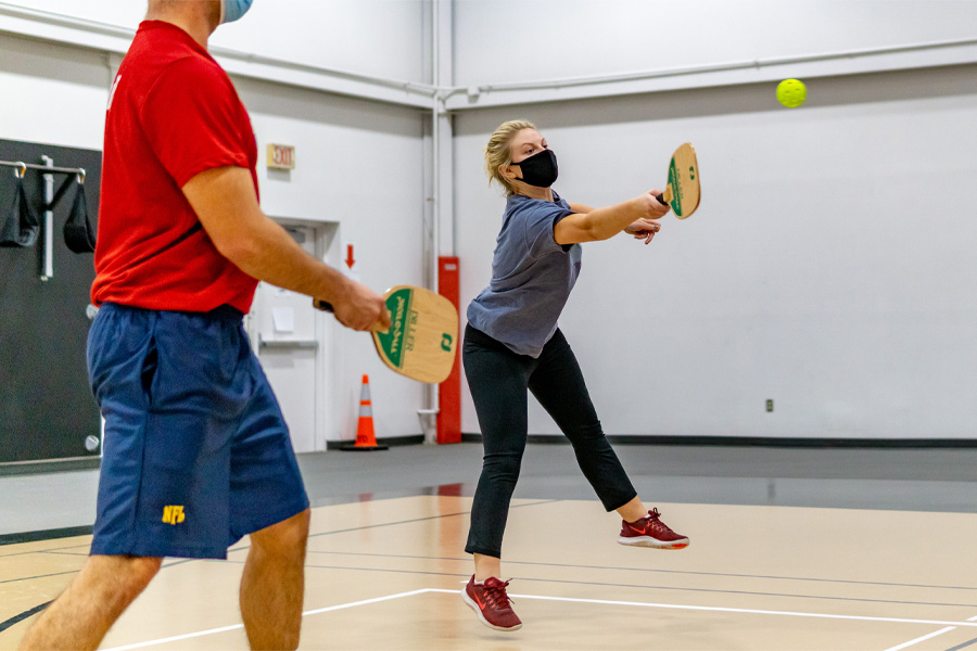 People play pickleball in a gymnasium