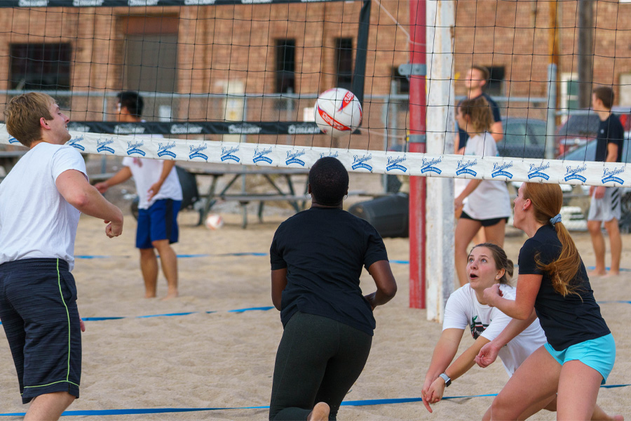 A group of people play sand volleyball