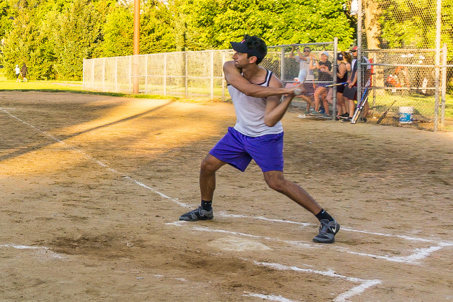 A man prepares to hit an incoming softball with a bat