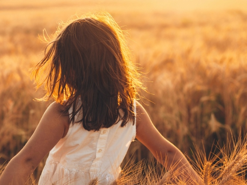 young girl walking through wheat field