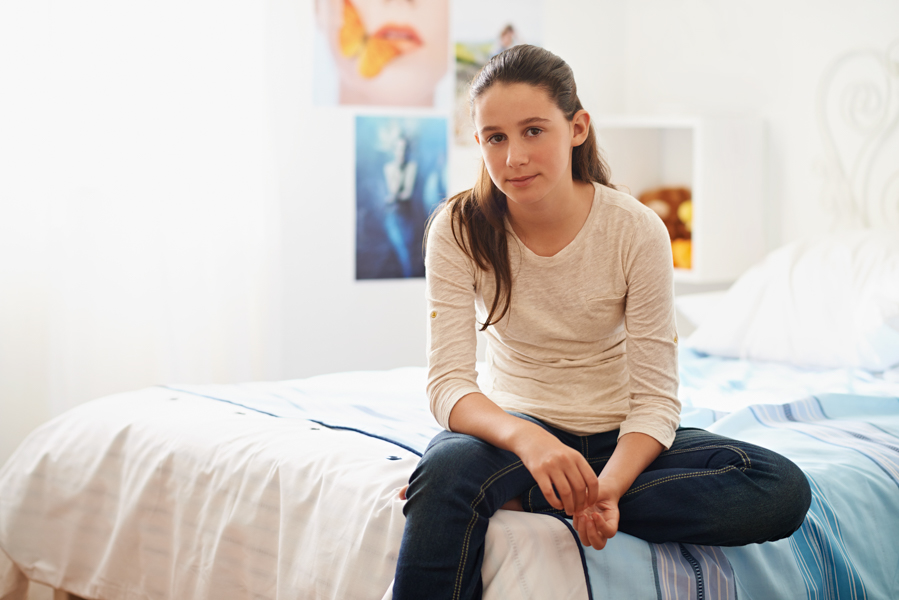 girl sitting on a bed looking troubled