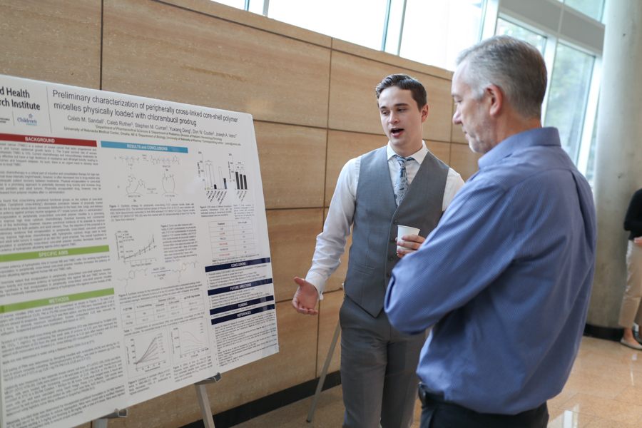 younger man explains scientific poster to older man
