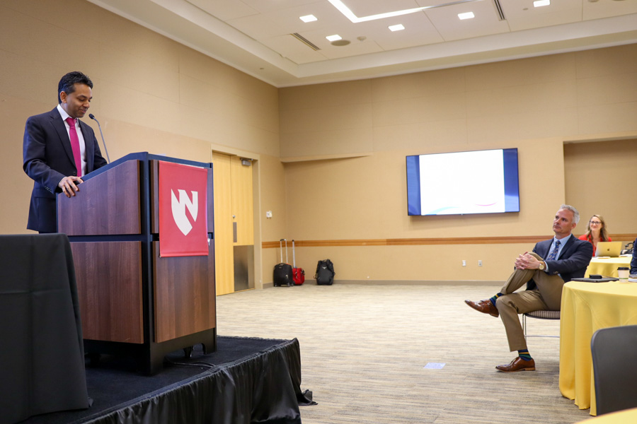 Don Coulter sits at table listening to Sidharth Mahapatra talking at symposium